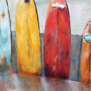 May include: Four vintage surfboards lined up on a beach, painted in shades of blue, yellow, red, and orange. The surfboards have a worn, weathered look, suggesting they have been used many times.