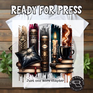 May include: White t-shirt with a graphic design featuring stacked books, a candle, and a coffee cup. The design includes the text "READY FOR PRESS" and "Just one more chapter."