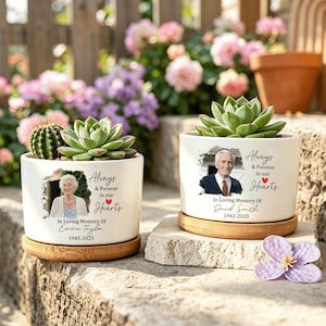 May include: Two white ceramic planters with bamboo bases, each featuring a printed portrait of a person, the text "Always & Forever in our Hearts," "In Loving Memory Of," a name, and dates. One contains a cactus and succulent, the other a succulent.