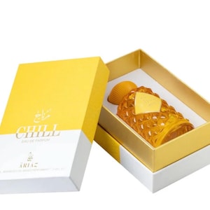 Puede incluir: Un frasco de perfume de color &aacute;mbar con un dise&ntilde;o texturizado &uacute;nico, presentado en una caja amarilla y blanca. La caja lleva la palabra "CHILL". El frasco tiene una etiqueta dorada.