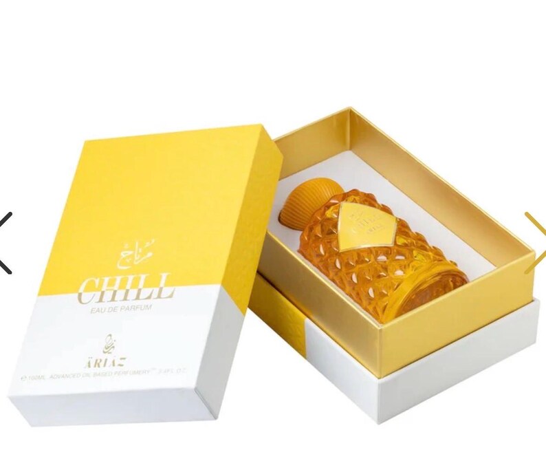Puede incluir: Un frasco de perfume de color &aacute;mbar con un dise&ntilde;o texturizado &uacute;nico, presentado en una caja amarilla y blanca. La caja lleva la palabra "CHILL". El frasco tiene una etiqueta dorada.