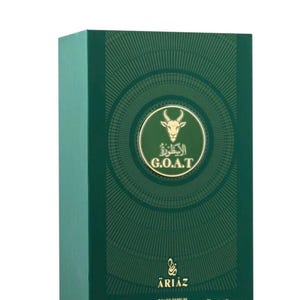 Puede incluir: Caja de perfume rectangular verde oscuro con detalles dorados. La caja presenta un emblema circular con una ilustración de cabra y el texto "G.O.A.T.". La parte inferior de la caja dice "ÄRIÁZ" y "EAU DE PARFUM e 100ml 3.4fl.oz."