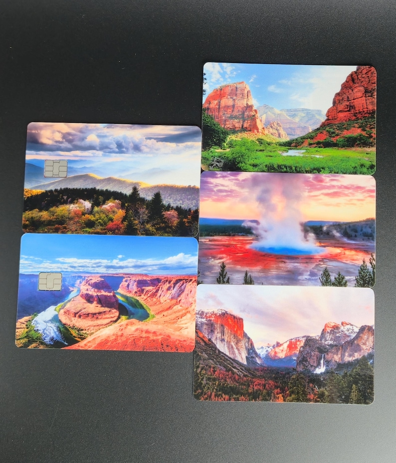 May include: A collection of five rectangular cards featuring scenic landscape images. The cards display various natural scenes, including mountains, canyons, and geysers, with vibrant colors and detailed imagery. Each card has a small, embedded chip.
