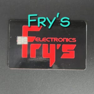 May include: A black rectangular card with the text "Fry's Electronics" in red and a turquoise "Fry's" logo. The card has a small embedded chip.