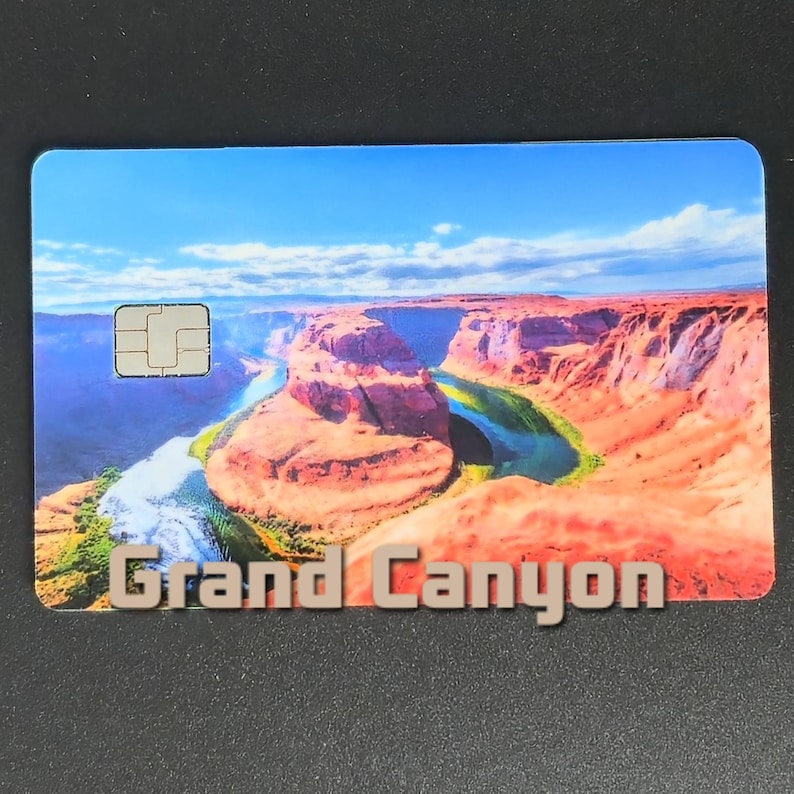 May include: A rectangular card featuring a scenic view of the Grand Canyon under a blue sky. The card displays the text "Grand Canyon" in a 3D font. A small chip is visible on the upper left corner.