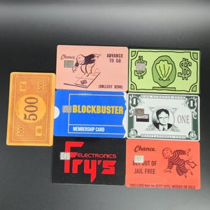 May include: A collection of novelty cards, including a $500 bill, a Blockbuster membership card, and cards with the Fry's Electronics logo. Other cards feature Monopoly-themed art and the text "Chance" and "Get Out of Jail Free."