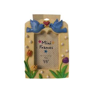 Puede incluir: Un marco de fotos rectangular amarillo con dos pájaros azules en la parte superior y un corazón rojo entre ellos. El marco está decorado con tulipanes naranjas, amarillos y morados en la base. El inserto dice Mini Frames for 5.7 cm x 8.3 cm Photos.