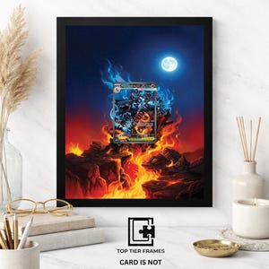 May include: Black framed 8x10 print featuring a fantasy scene with a full moon, flames, and a trading card. The card depicts a character with blue and orange accents. Text on the frame reads "8X10 FRAME". The bottom of the frame reads "TOP TIER FRAMES CARD IS NOT INCLUDED".