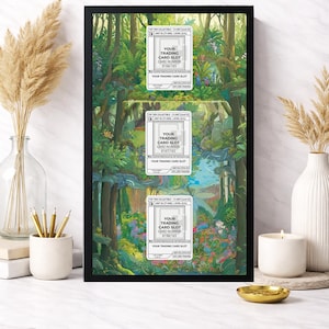 May include: A framed artwork featuring three trading card slots with card numbers #166/165, #167/165, and #198/165. The background is a vibrant forest scene with lush greenery and a flowing river. The frame is black.