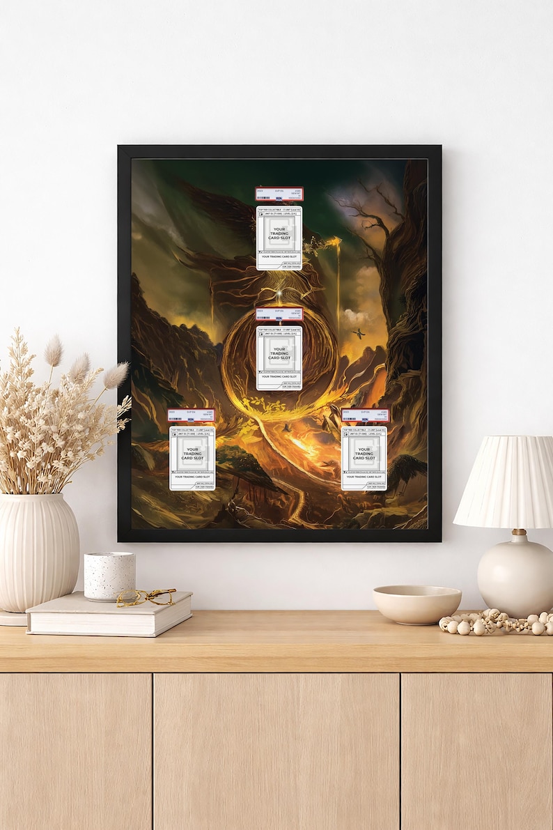 May include: Framed artwork featuring a fantasy landscape with a golden portal and several trading card holders. The cards are labeled "YOUR TRADING CARD SLOT". The artwork is displayed on a wooden cabinet with a lamp and decorative items.