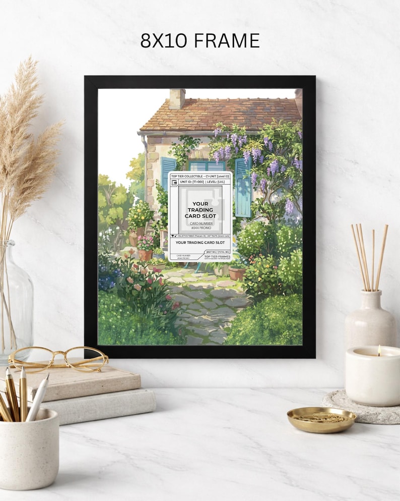 May include: Black 8x10 frame with a watercolor print of a European cottage with blue shutters, surrounded by lush greenery and flowers. The print includes text that reads "YOUR TRADING CARD SLOT".