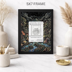 May include: A black 5x7 frame displays a colorful fantasy illustration with a trading card slot. The artwork features a detailed landscape with creatures, trees, and a river. The text on the card reads "YOUR TRADING CARD SLOT CARD NUMBER #203/193".