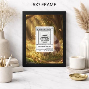 Op de afbeelding: Een zwarte 5x7 frame toont een trading card slot met de tekst "YOUR TRADING CARD SLOT" en kaartnummer #168/159. De lijst bevat een afbeelding van een boslandschap met een wasbeer.