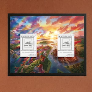May include: Framed artwork featuring a vibrant landscape with a colorful sky and a river running through a town. Two white rectangles with text, "YOUR TRADING CARD SLOT", are overlaid on the image. The frame is black.