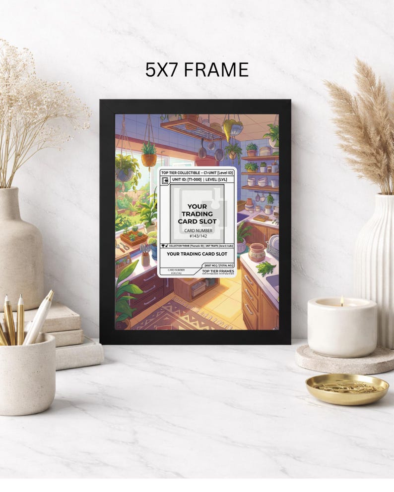 May include: A black 5x7 frame with a colorful illustration of a kitchen scene. The artwork includes text that reads "YOUR TRADING CARD SLOT" and "TOP TIER FRAMES". The frame is displayed on a white marble surface.