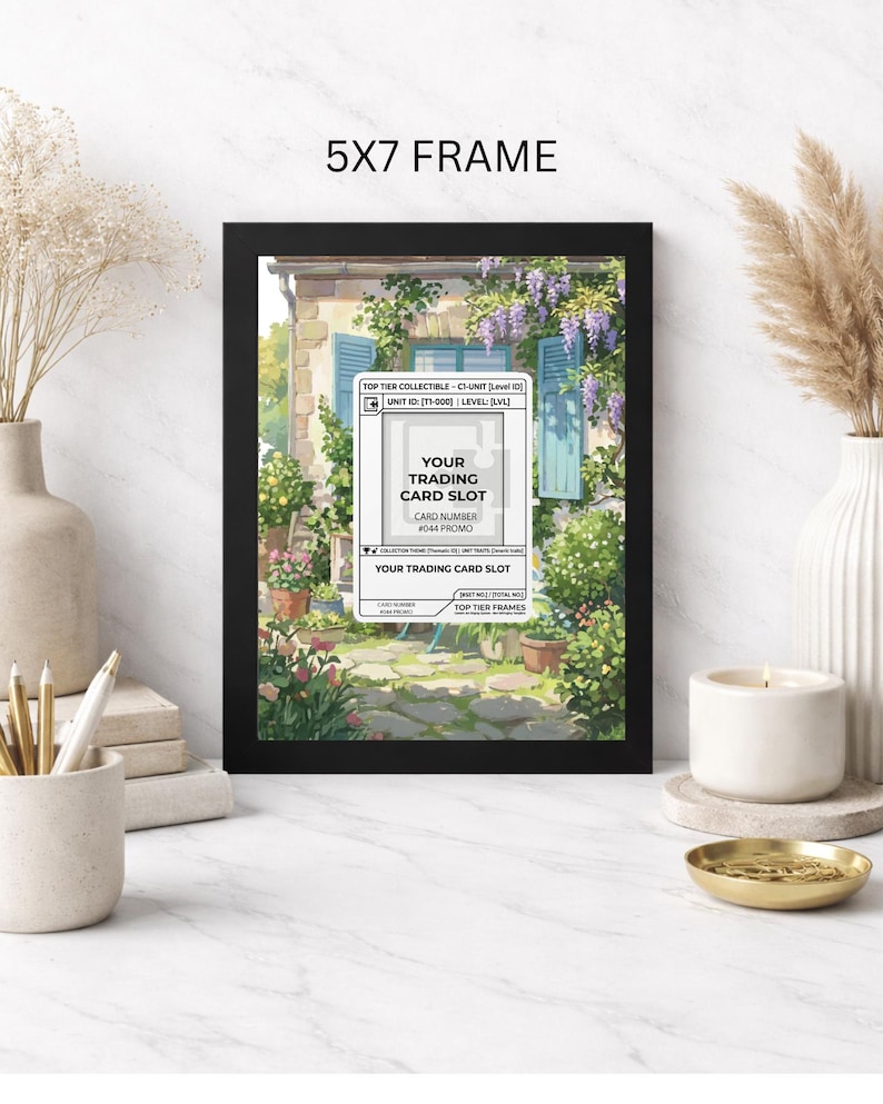 May include: A black 5x7 frame displaying a colorful print of a European-style building with blue shutters and lush greenery. The frame includes a white card slot for trading cards with text that reads "YOUR TRADING CARD SLOT".