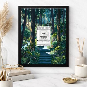 May include: A framed 8x10 print featuring a forest scene with a path leading through trees. The artwork includes a white label with the text "YOUR TRADING CARD SLOT" and a card number. The frame is black.