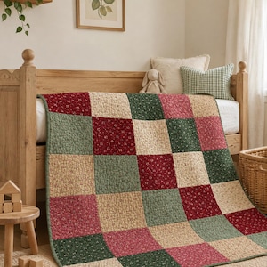 May include: A patchwork quilt featuring a grid of square fabric panels in alternating colors of deep red, sage green, and cream, each decorated with a small-scale floral print. The quilt is draped over a wooden bed frame in a room setting.