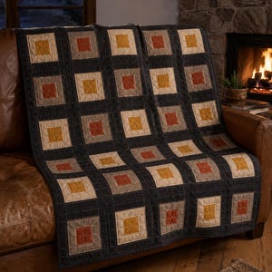 May include: A quilt featuring a grid pattern of square blocks in shades of mustard yellow, burnt orange, and light grey, all framed by dark charcoal grey borders. The fabric has visible quilted stitching lines throughout the entire surface.
