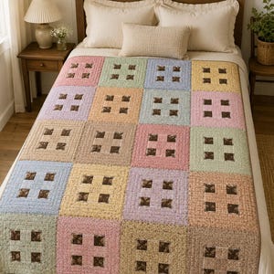 May include: A patchwork quilt featuring a grid of square blocks in pastel shades of pink, blue, yellow, and green. Each block contains a central four-patch design made of dark brown fabric with a small floral pattern, surrounded by solid-colored borders.