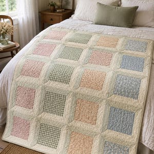 Op de afbeelding: Een patchwork quilt met een raster van vierkante stoffen panelen in zachte tinten roze, saliegroen, perzik en lichtblauw. De vierkanten worden gescheiden door crèmekleurige banen en zijn voorzien van diverse bloemenprints en een groen ruitpatroon.