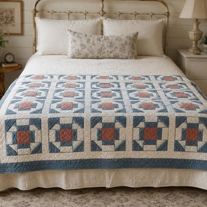 May include: A quilt featuring a repeating geometric block pattern in shades of dusty blue, terracotta, and cream. The design consists of a central terracotta square surrounded by blue and cream triangles and squares, finished with a blue border.