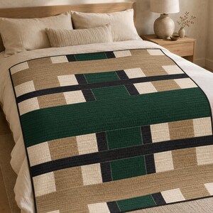 Könnte beinhalten: Eine rechteckige Steppdecke mit einem geometrischen Muster aus abwechselnden Blöcken in Waldgrün, Beige und Creme. Das Design besteht aus horizontalen und vertikalen Bändern in Unifarben mit einer sichtbaren Steppstruktur auf der Stoffoberfläche.