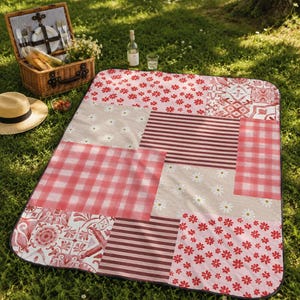 May include: A patchwork picnic blanket with various patterns, including gingham, stripes, and floral designs in shades of red, pink, and beige. A picnic basket, straw hat, and wine bottle are nearby on the grass.