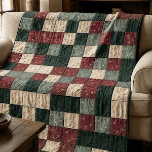 Puede incluir: Una colcha de patchwork con un patrón de cuadrícula repetitivo de bloques de tela cuadrados en verde bosque profundo, burdeos apagado y crema. Los cuadrados de color crema están decorados con un pequeño y delicado estampado floral en la tela.