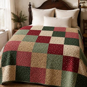 May include: A patchwork quilt featuring a repeating grid of square fabric panels in shades of deep red, forest green, and cream. Each square is decorated with a small-scale floral print pattern, and the entire quilt has a quilted texture.