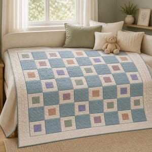 May include: A patchwork quilt featuring a repeating grid pattern of light blue, cream, sage green, lavender, and dusty rose squares. The quilt has a textured, quilted surface and is draped over a daybed with several decorative pillows.
