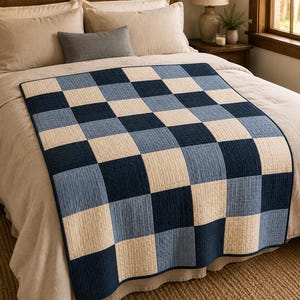 May include: A rectangular quilt featuring a repeating checkerboard pattern in alternating squares of dark navy blue, medium denim blue, and off-white. The fabric surface displays a fine, vertical stitched texture throughout the entire design.