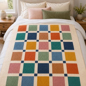 May include: A quilt featuring a grid of multicoloured squares in shades of orange, teal, blue, yellow, and pink, separated by thin cream-coloured borders and small dark blue corner squares, with a textured surface and a solid cream-coloured border.