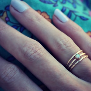 May include: A gold ring with three bands and a small opal stone in the center.
