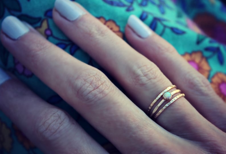 May include: A gold ring with three bands and a small opal stone in the center.