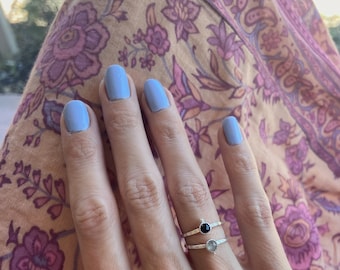 Peut inclure: Deux bagues en argent avec des anneaux texturés portées sur un doigt. La bague supérieure présente une petite pierre noire ronde à facettes, tandis que la bague inférieure porte une petite pierre gris clair ronde à facettes.
