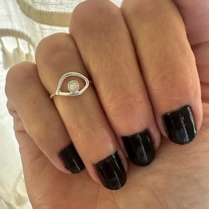 May include: A silver ring with an opal stone in the shape of an eye.