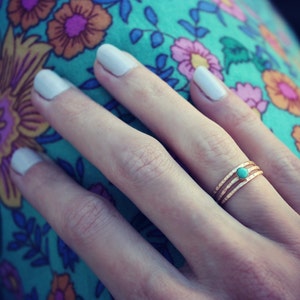 May include: A gold ring with three bands and a turquoise stone in the center.