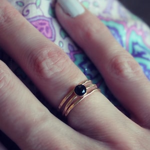 May include: A gold ring with three bands and a black gemstone in the center.