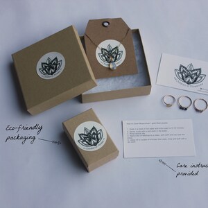 May include: A set of eco-friendly packaging for jewelry. The packaging includes a brown box with a white sticker that says "Garden of Flowers", a small brown box with a white sticker that says "Garden of Flowers", a white card with care instructions, and three gold rings with different stones.