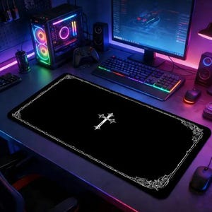 May include: A rectangular black desk mat featuring a white cross centered on the surface and a white decorative border pattern along the edges. The mat is positioned on a desk in front of a computer monitor, keyboard, and gaming computer tower.