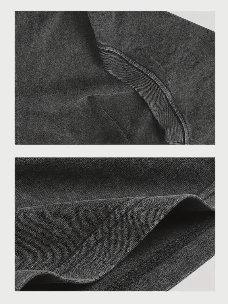 May include: A charcoal grey t-shirt featuring a washed, faded fabric texture. The garment displays a ribbed crew neckline and double-stitched hem detailing on the sleeves and bottom edge, showcasing the soft, worn-in appearance of the cotton material.