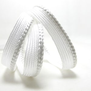 May include: Close-up of white shoelaces, tightly woven with a textured surface. The laces are looped and curved, creating a dynamic shape against a white background. The shoelaces are a bright, clean white.