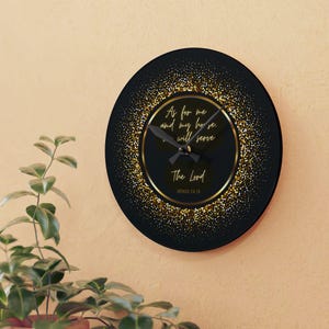 May include: A round black wall clock with gold detailing and the text "As for me and my house, we will serve The Lord Joshua 24:15". The clock has a gold border and a gold glitter effect.