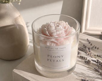 Bougie artisanale en cire de soja, parfumée et florale, avec une rose en guise de capuchon et des pétales de pivoine. Idéale comme cadeau de décoration.