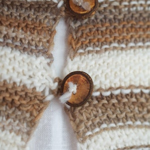 May include: A close-up of a brown and white striped knitted cardigan with two wooden buttons.