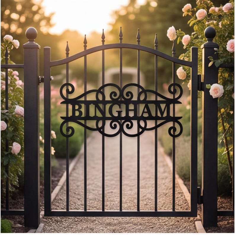 以下が含まれることがあります： 中央の水平パネルに大文字で「BINGHAM」と記された黒い金属製のガーデンゲート。ゲートには垂直の格子、先端が尖ったアーチ状の上部レール、そしてネームプレートを囲む装飾的なスクロール模様が施されています。