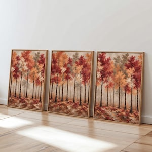 Könnte beinhalten: Ein Set aus drei rechteckigen Wandbildern in hellen Holzrahmen, die jeweils eine Waldszene mit Bäumen in herbstlichen Farben wie Rot, Orange und Gelb vor einem weichen, nebligen und neutralen Hintergrund darstellen.