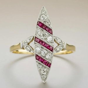 Peut inclure: Une bague en forme de marquise présentant un motif rayé diagonal de rubis rouges taille carrée et de diamants blancs ronds sertis dans un métal argenté. Le design central allongé est flanqué de petites feuilles ornées de diamants sur un anneau doré.