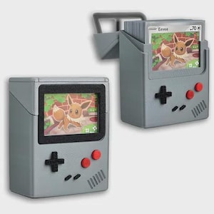 Könnte beinhalten: Grauer Kartenhalter in Form einer Retro-Handheld-Spielkonsole mit einem Bildschirm, der eine Evoli-Pokémon-Karte anzeigt. Der Halter hat ein schwarzes Steuerkreuz, rote Knöpfe und einen Griff. Der zweite Halter ist offen und zeigt mehrere Evoli-Karten.